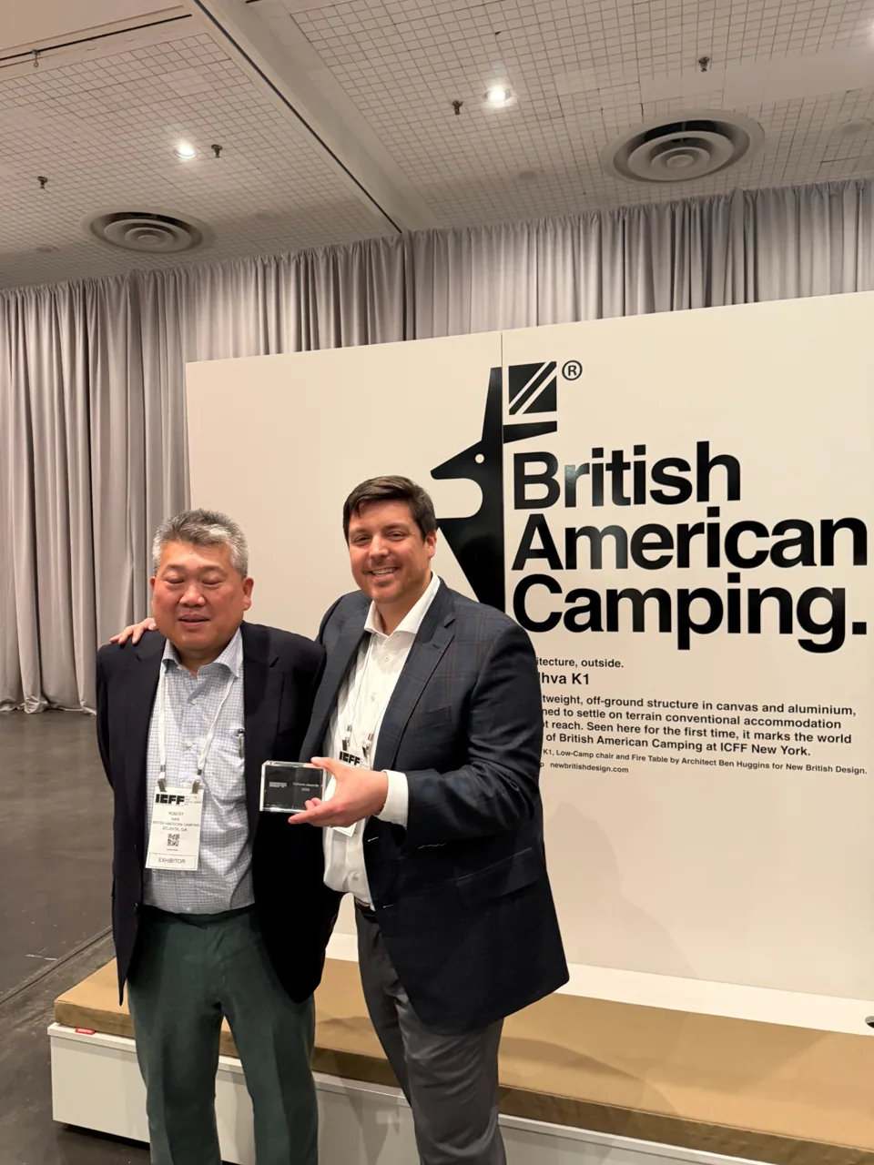 Two attendees holding the ICFF Editors Award at the British American Camping exhibit.